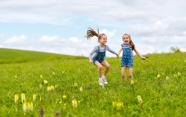 Bambini felici gemelle sorelle che saltano e ridono in estate — Foto Stock