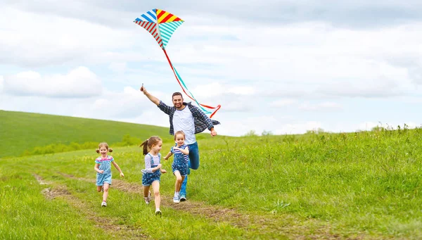 Feliz familia padre e hijos corren con cometa en el prado —  Fotos de Stock