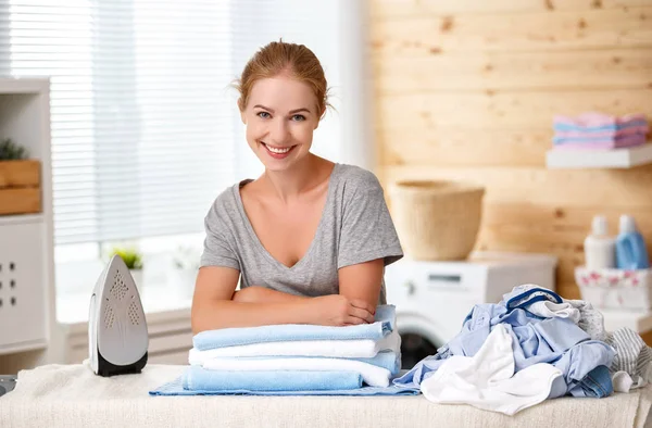 Mulher feliz dona de casa roupa de engomar na lavanderia em hom — Fotografia de Stock
