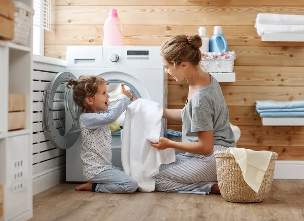 Feliz familia madre ama de casa y el niño en la lavandería con lavabo — Foto de Stock