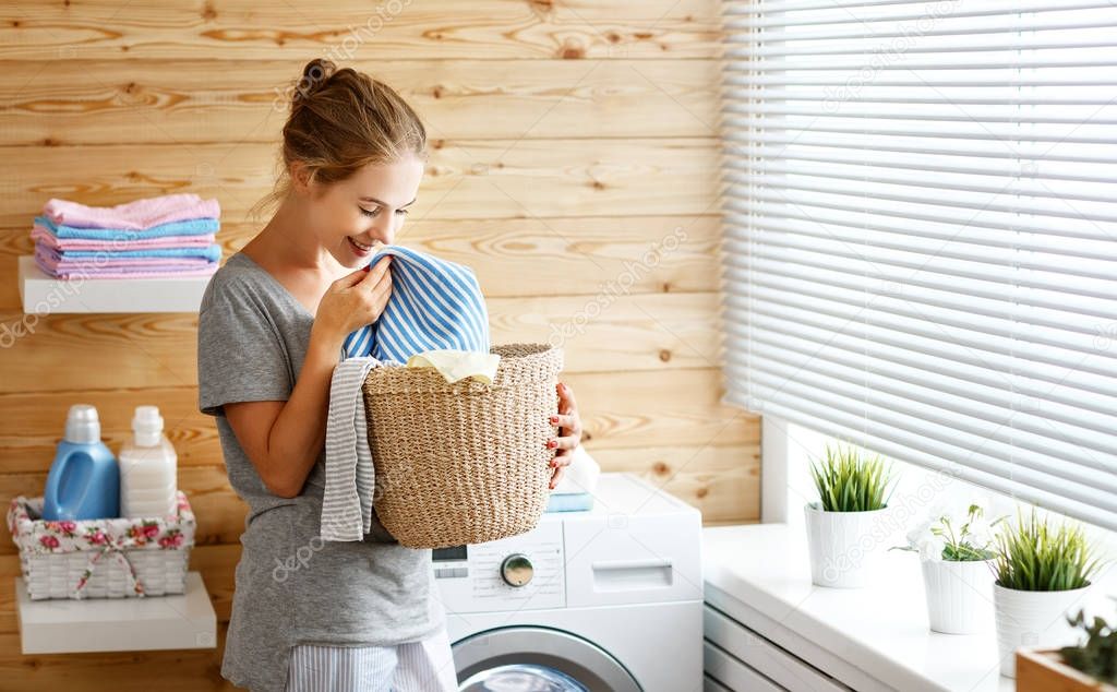 Happy housewife woman in laundry room with washing machine 