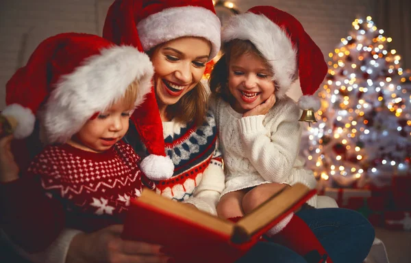 Familie moeder en kinderen lezen een boek met Kerstmis in de buurt van firep — Stockfoto