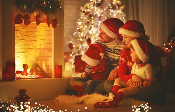Feliz familia sentada junto a la chimenea en Navidad Ev — Foto de Stock