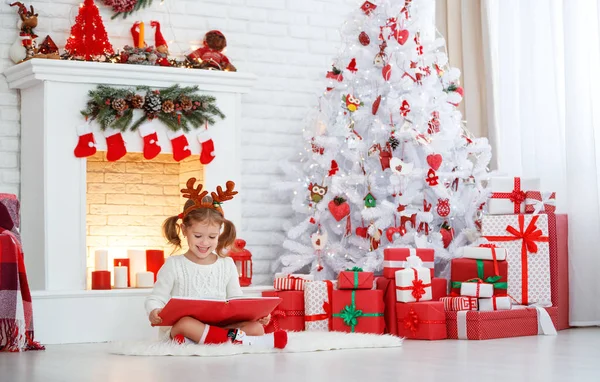 Heureux enfant fille lecture livre le matin à l'arbre de Noël — Photo