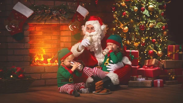 Natale. Babbo Natale con elfi bere latte e mangiare biscotti — Foto Stock