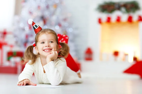 Criança menina escrevendo carta santa casa perto da árvore de Natal — Fotografia de Stock