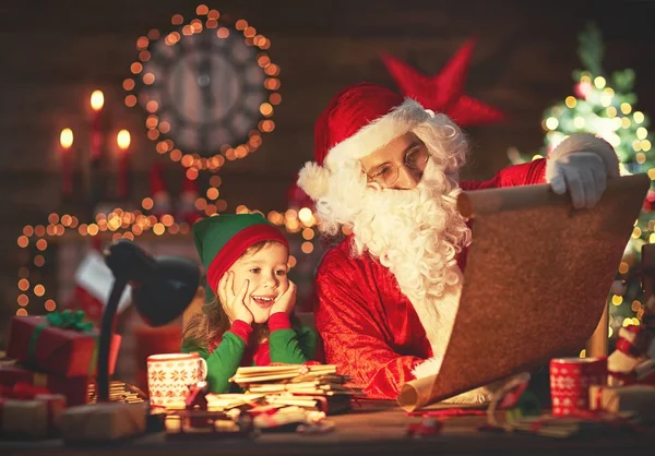 Santa claus lê lista de boas crianças para pequeno elfo por Christm — Fotografia de Stock