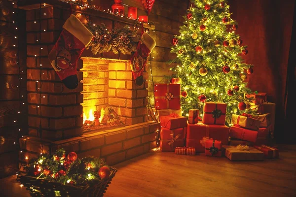 Navidad interior. árbol resplandeciente mágico, regalos de chimenea en la oscuridad — Foto de Stock