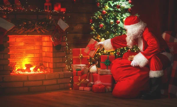 Veselé Vánoce! Santa claus v blízkosti krbu a strom se zeměpisným označením — Stock fotografie