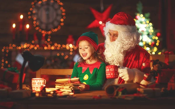 Santa claus lee carta a pequeño elfo por árbol de Navidad — Foto de Stock