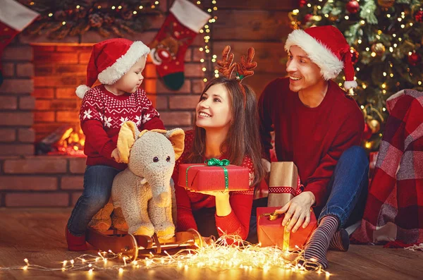 Gelukkig gezin moeder vader en baby bij kerstboom thuis — Stockfoto