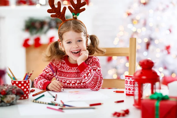 Barn tjej skriver brev santa hem nära julgran — Stockfoto