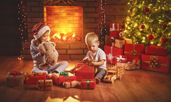 Ευτυχισμένα παιδιά Ανοίξτε τα δώρα Χριστουγέννων το βράδυ στο χριστουγεννιάτικο δέντρο — Φωτογραφία Αρχείου