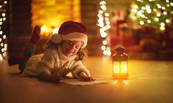 Dítě dívka psát dopis santa domě u vánočního stromu — Stock fotografie