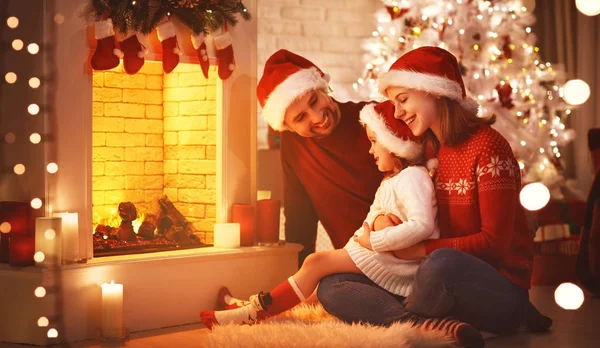 Famiglia felice seduta vicino al camino la vigilia di Natale — Foto Stock