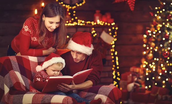 Vrolijk kerstfeest! familie-moeder, vader en baby Lees boek in de buurt van tr — Stockfoto