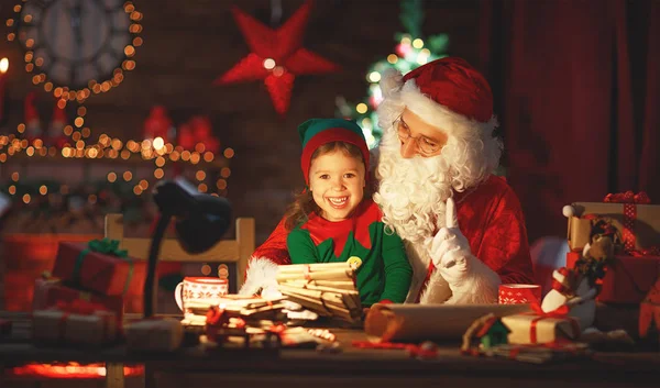 Santa claus läser brev till lille tomten med julgran — Stockfoto
