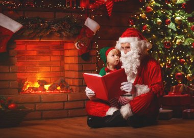 Noel Baba Noel ağacı tarafından küçük bir elf için bir kitap okur