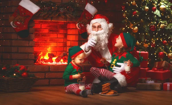 Vánoce. Santa Claus s elfy pít mléko a jíst soubory cookie — Stock fotografie