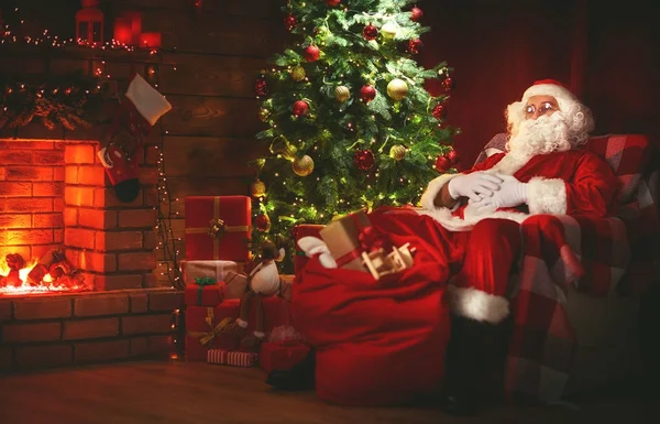 Veselé Vánoce! Santa claus v blízkosti krbu a strom se zeměpisným označením — Stock fotografie