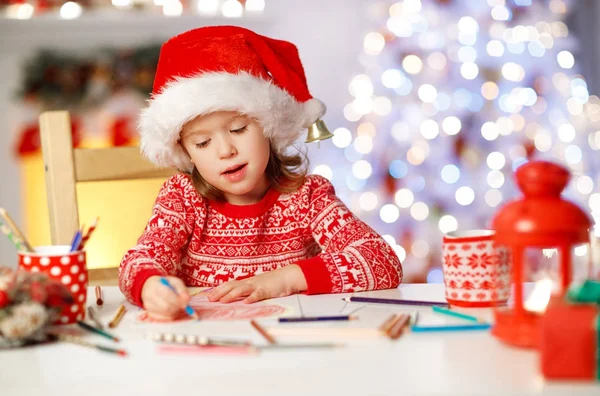 Barn tjej skriver brev santa hem nära julgran — Stockfoto