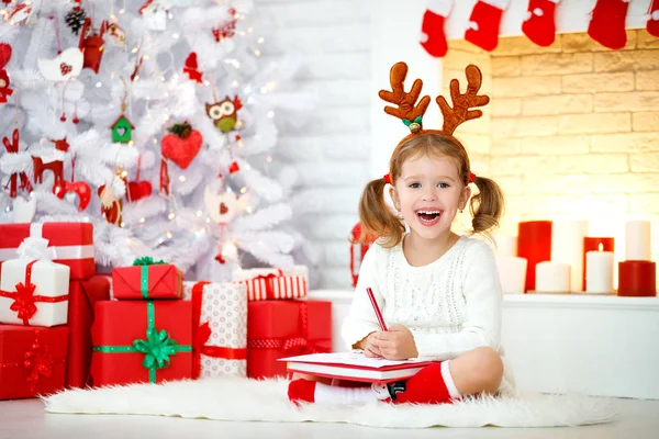 Criança menina escrevendo carta santa casa perto de natal tre — Fotografia de Stock