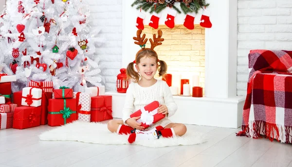 Gelukkig kind meisje met cadeau in ochtend bij de kerstboom — Stockfoto