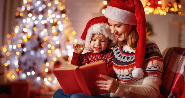 Nochebuena. familia madre y bebé leyendo libro de magia en casa — Foto de Stock