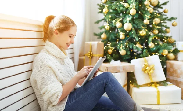 Gelukkige vrouw met tablet pc op ochtend in de buurt van de kerstboom — Stockfoto