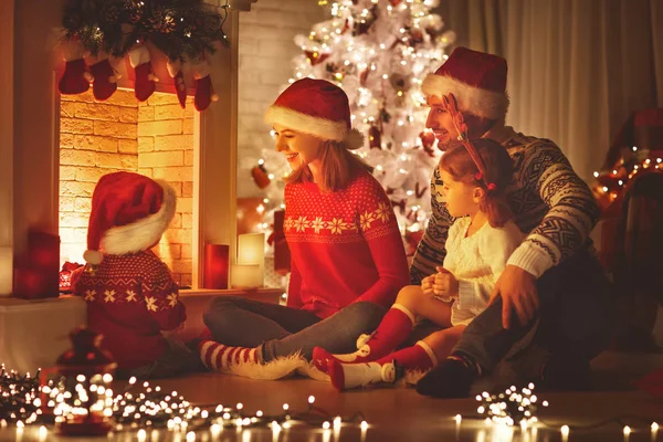 Happy family sitting by fireplace on Christmas Eve — Stock Photo, Image