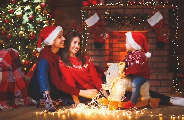 Gelukkig gezin moeder vader en baby bij kerstboom thuis — Stockfoto