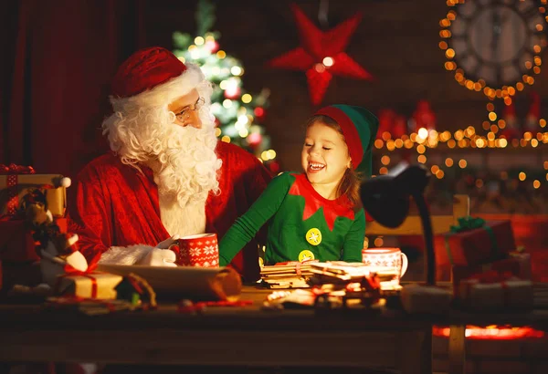 Papai Noel lê carta ao pequeno elfo pela árvore de Natal — Fotografia de Stock