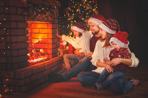 Šťastná rodina sedí u krbu na Štědrý den — Stock fotografie