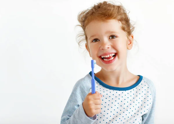 En glad jente smiler med tannbørste – stockfoto