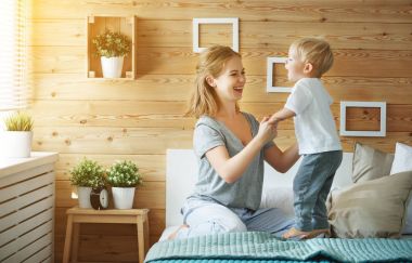 mutlu aile anne ve bebek evlat yürümeye başlayan çocuk yatakta gülüyor