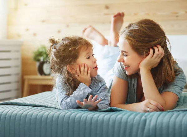 Yatakta gülerek mutlu aile anne ve çocuk kızı — Stok fotoğraf