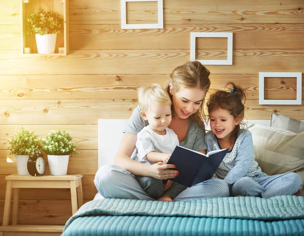 Family mother reading to  children book in be — Stock Photo, Image