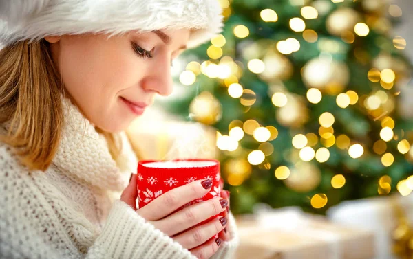 Ευτυχισμένη γυναίκα με μια κούπα τσάι κοντά στο χριστουγεννιάτικο δέντρο — Φωτογραφία Αρχείου