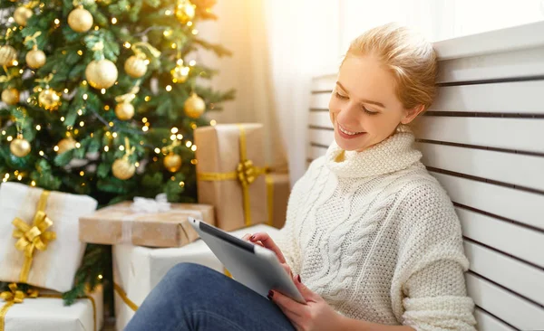 Gelukkige vrouw met tablet pc op ochtend in de buurt van de kerstboom — Stockfoto