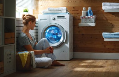 Çamaşır odasında çamaşır makinesiyle mutlu ev kadını  