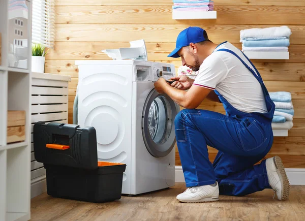 Trabalho homem encanador reparos máquina de lavar roupa na lavanderia — Fotografia de Stock