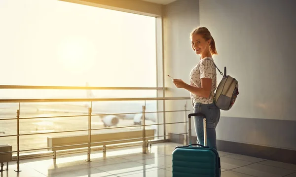 Ung kvinna väntar flyger på flygplatsen på fönster med väskorna — Stockfoto