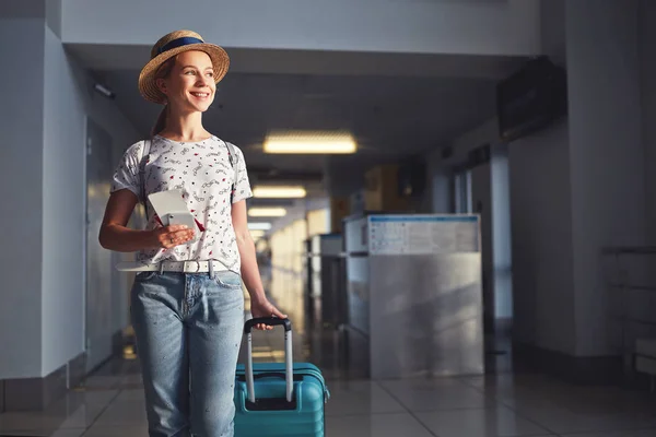 Молода жінка йде в аеропорт біля вікна з валізою чекає — стокове фото