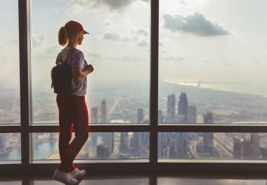 girl tourist at window of skyscraper of the Burj Khalifa in Duba clipart