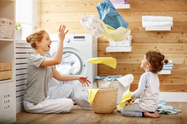 Lycklig familj mamma hemmafru och barn i tvättstuga med tvättmaskin — Stockfoto