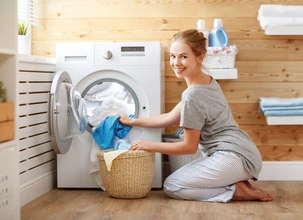 Mulher dona de casa feliz na lavanderia com máquina de lavar roupa — Fotografia de Stock