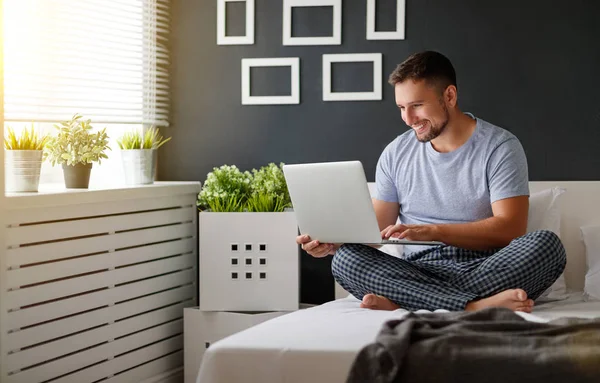 Glad ung man med laptop och fika i sängen — Stockfoto