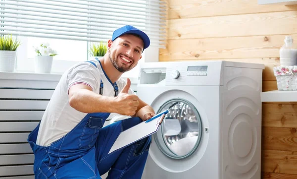 Trabalho homem encanador reparos máquina de lavar roupa na lavanderia — Fotografia de Stock