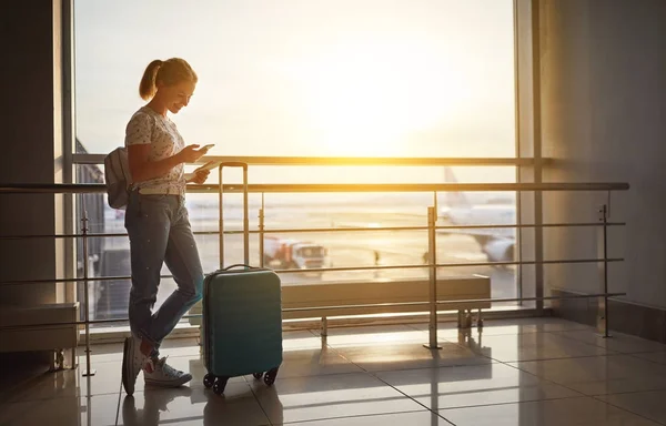 Jonge vrouw te wachten voor het vliegen op de luchthaven bij raam met suitcas — Stockfoto