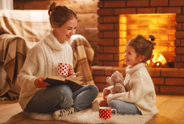 Family mother and child reading book on winter evening by firepl Royalty Free Stock Images